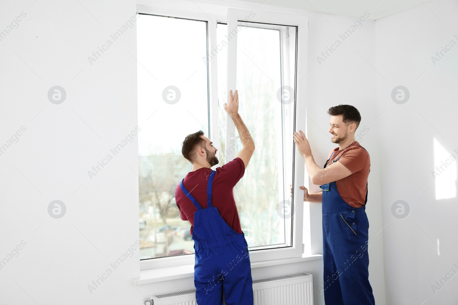 Photo of Construction workers installing plastic window in house