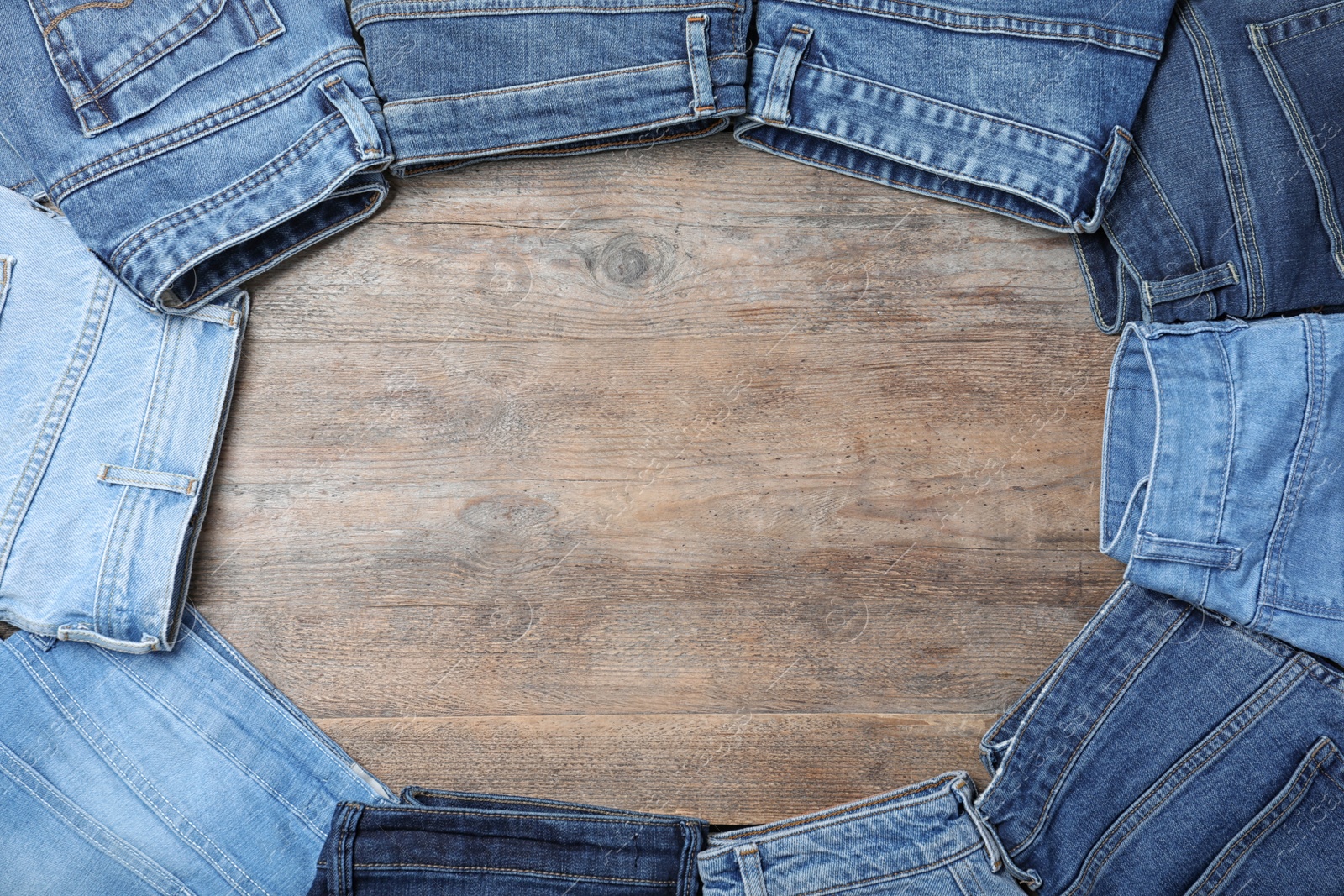 Photo of Frame made of stylish jeans on wooden background, flat lay. Space for text