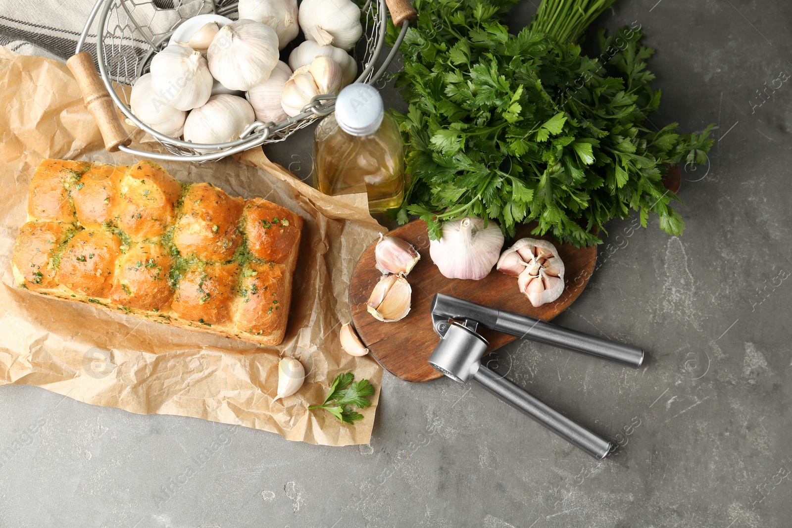 Photo of Buns of bread with garlic and herbs on grey table, flat lay