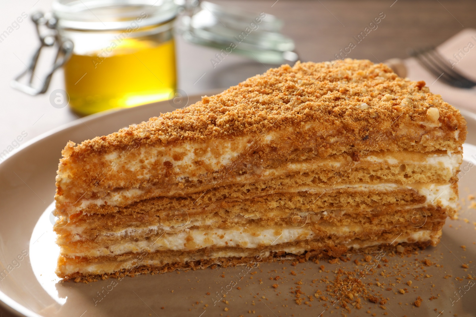Photo of Slice of delicious layered honey cake on plate, closeup