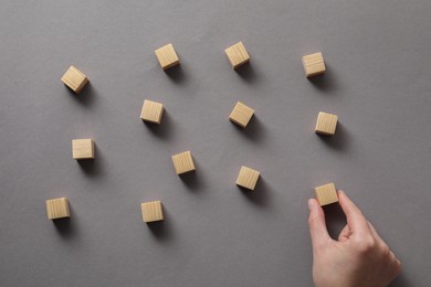Photo of Woman arranging wooden cubes at grey table, top view
