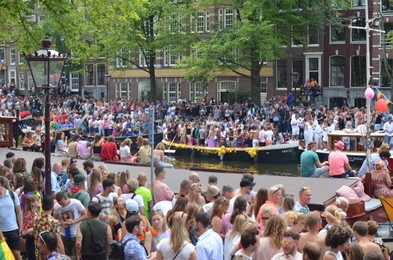 Photo of AMSTERDAM, NETHERLANDS - AUGUST 06, 2022: Many people in boats at LGBT pride parade on river