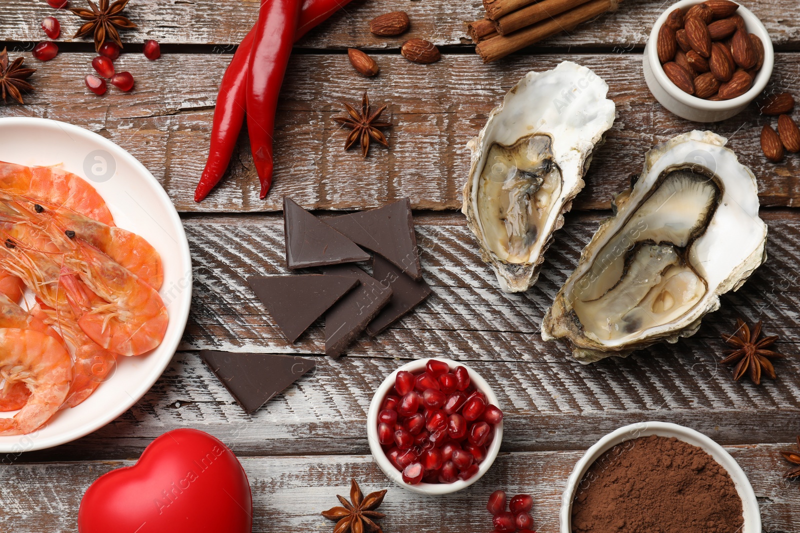 Photo of Natural aphrodisiac. Different food products and heart model on wooden table, flat lay