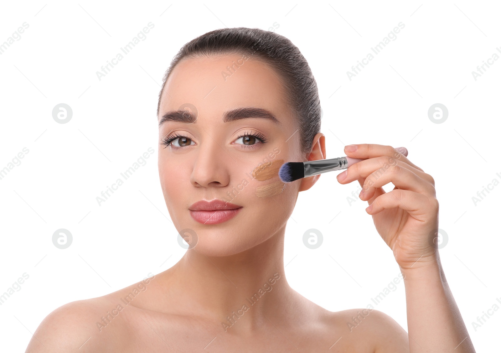 Photo of Woman applying foundation on face with brush against white background