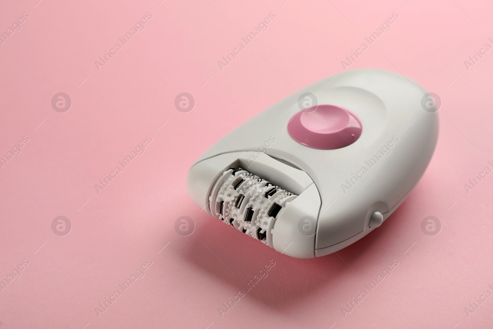 Photo of Modern epilator on pink background, space for text