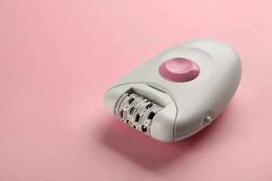 Modern epilator on pink background, space for text