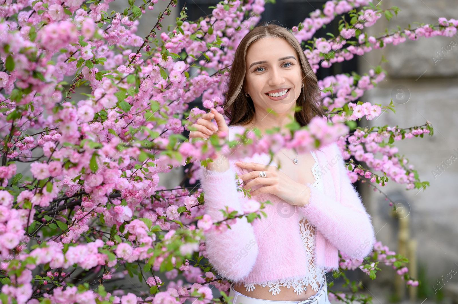 Photo of Beautiful young woman near blossoming sakura tree on spring day