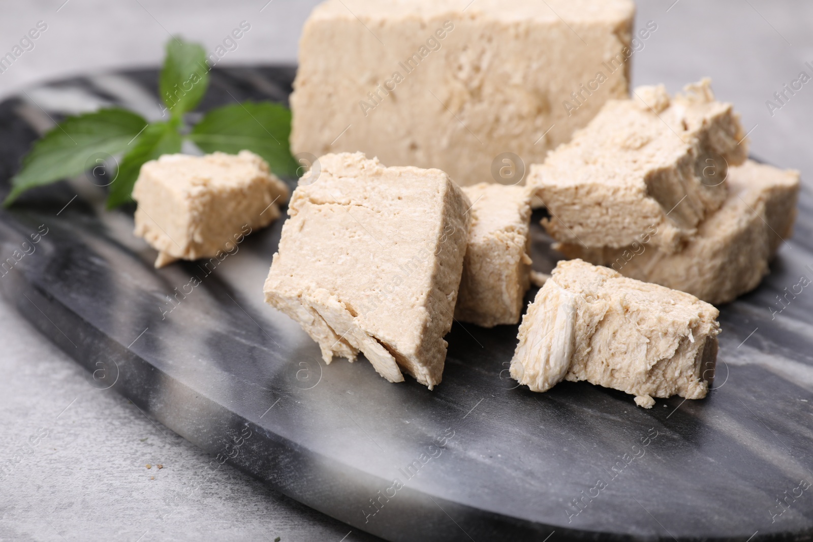 Photo of Pieces of tasty halva and mint served on light grey table, closeup