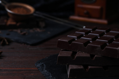 Photo of Tasty dark chocolate bars on wooden table, closeup