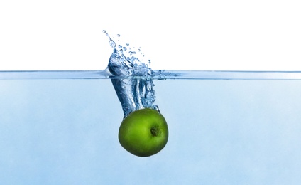 Apple falling down into clear water against white background