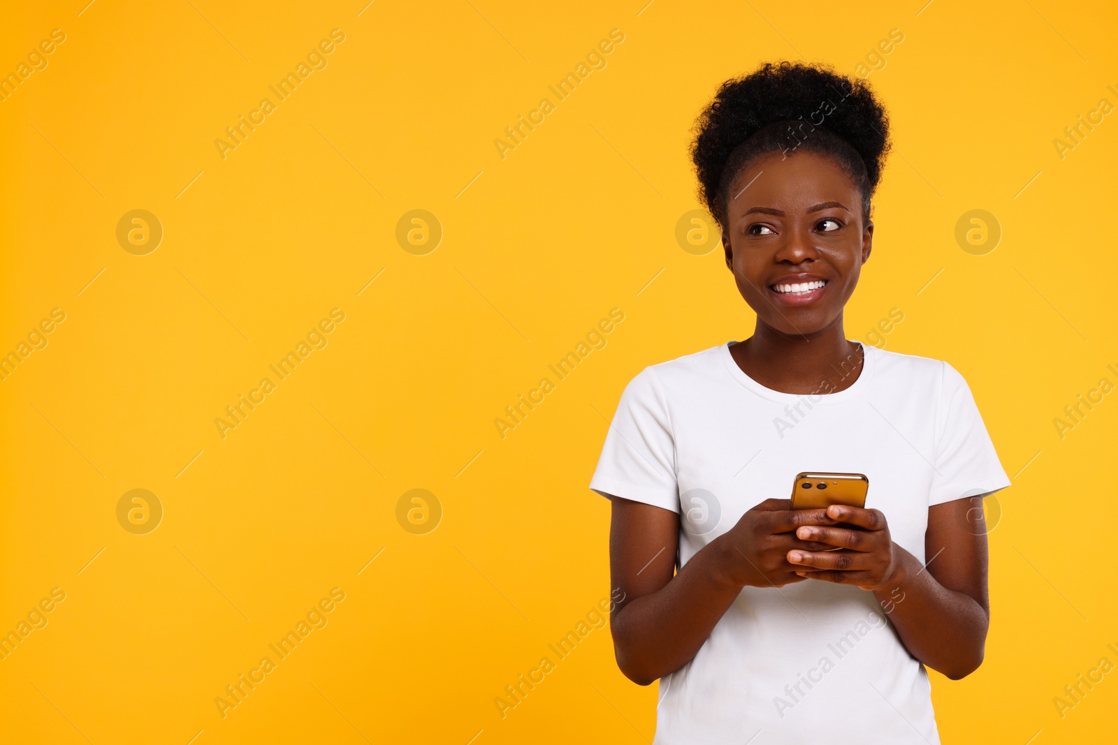 Photo of Happy young woman with smartphone on orange background. Space for text