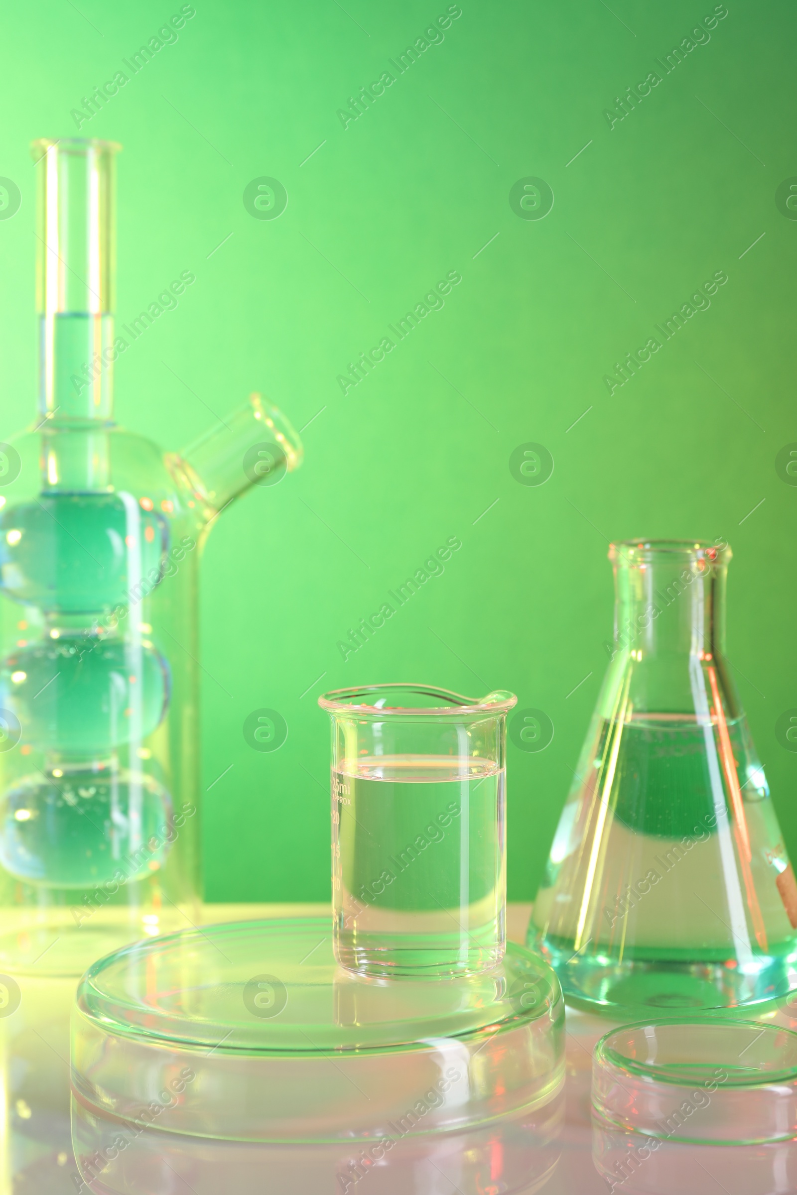 Photo of Laboratory analysis. Different glassware on table against green background, space for text