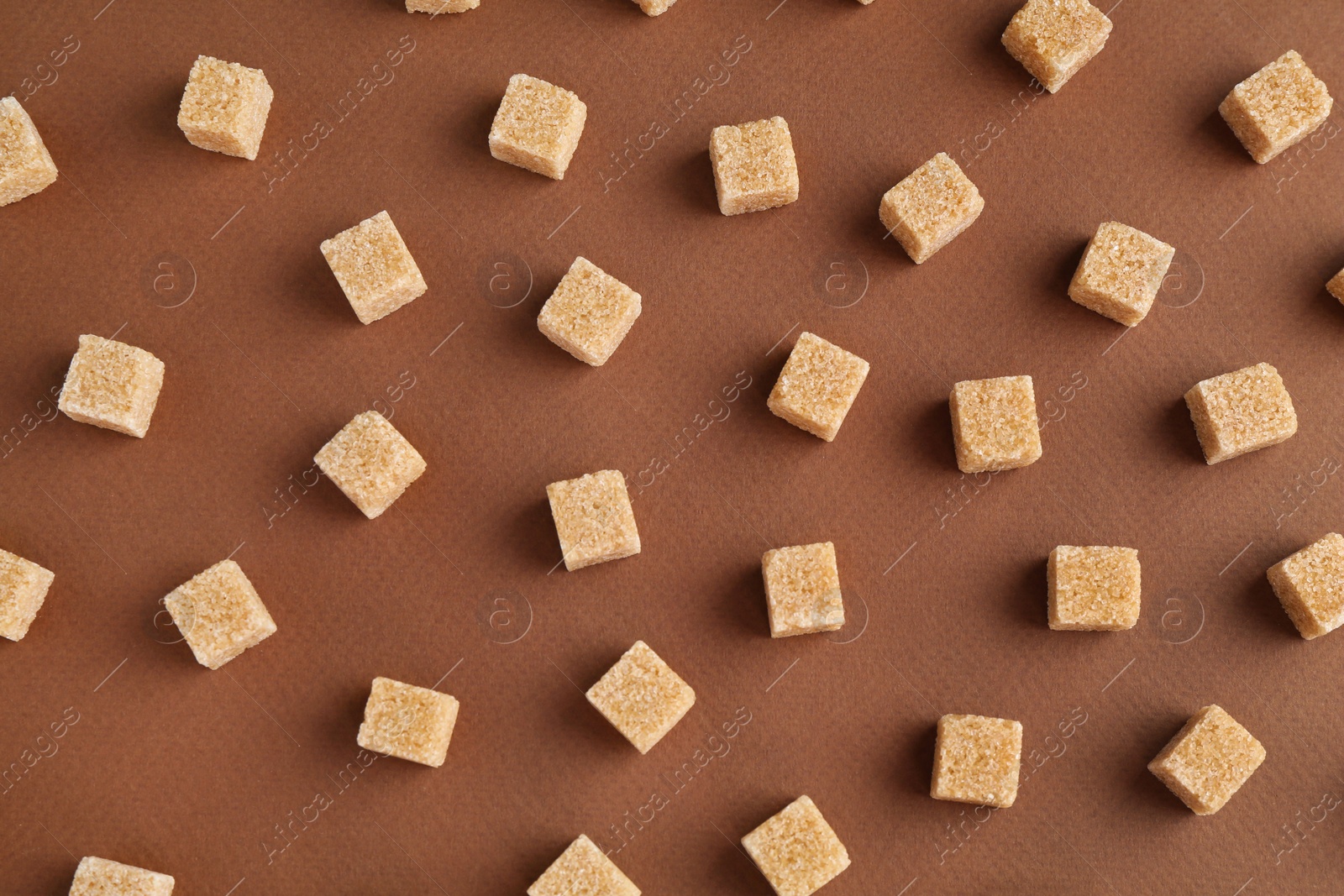 Photo of Brown sugar cubes on color background, top view