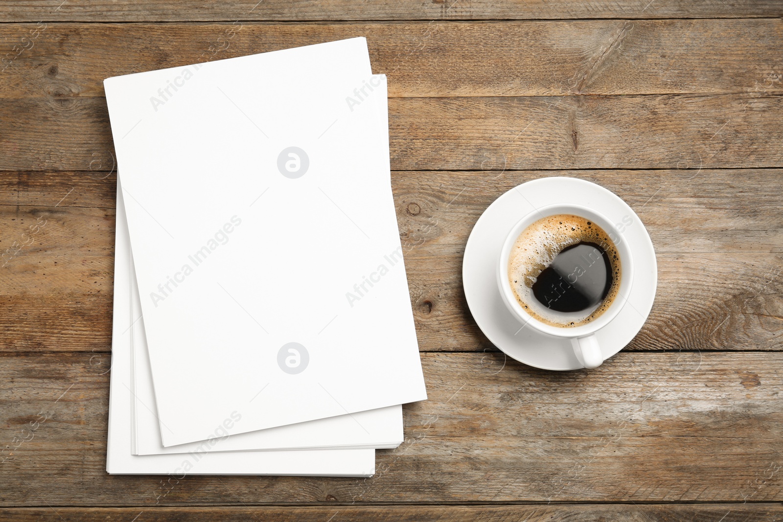 Photo of Blank paper sheets for brochure and cup of coffee on wooden background, flat lay. Mock up