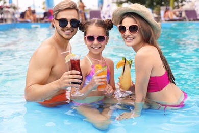 Photo of Happy family with cocktails in pool on sunny day