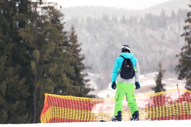 Snowboarder on slope at resort, space for text. Winter vacation