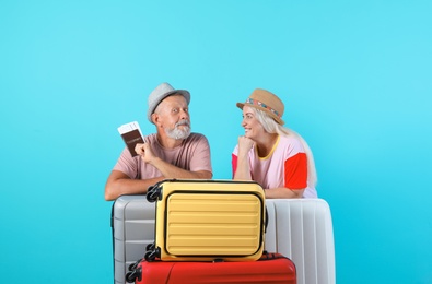 Photo of Senior couple with suitcases and passport on color background. Vacation travel