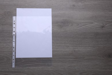 Photo of Punched pocket with paper sheet on wooden table, top view. Space for text