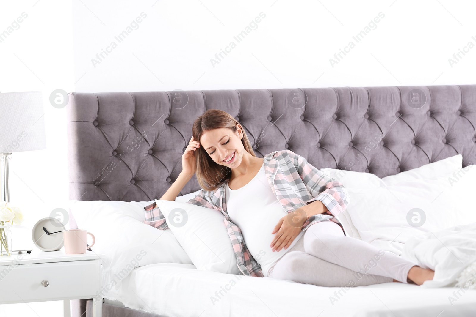 Photo of Happy pregnant woman lying in bed at home