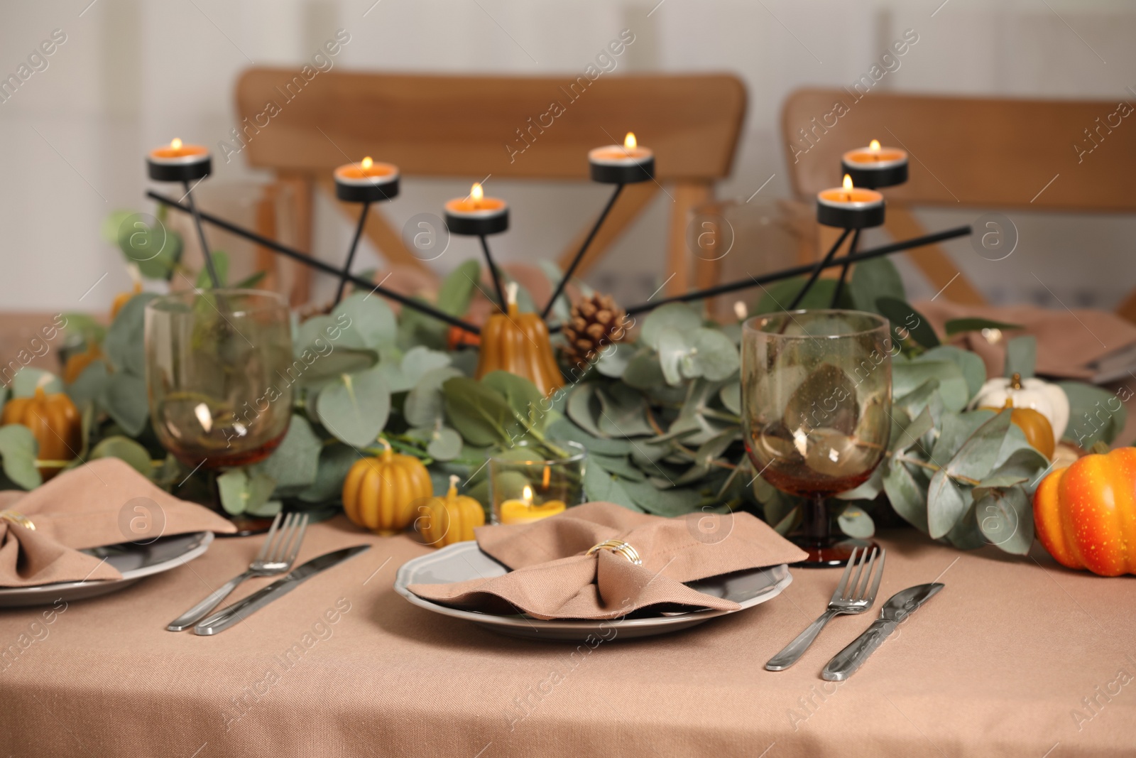 Photo of Autumn table setting with eucalyptus branches and pumpkins indoors