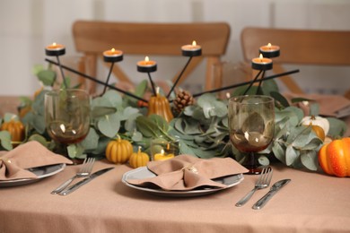 Photo of Autumn table setting with eucalyptus branches and pumpkins indoors