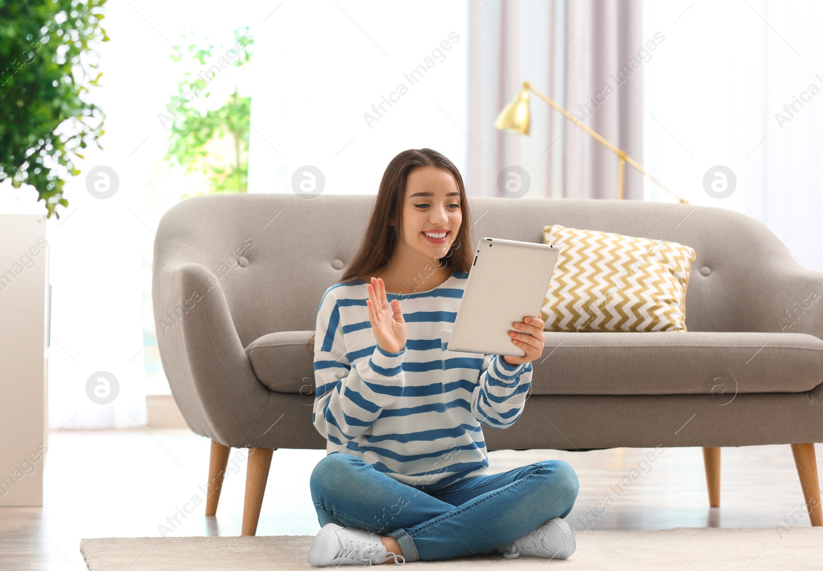 Photo of Woman using tablet for video chat in living room