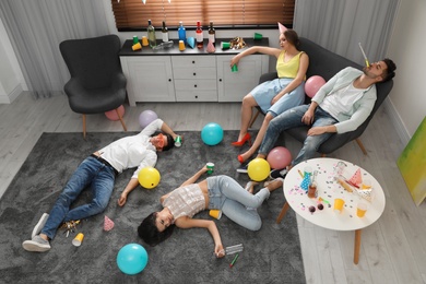 Group of friends sleeping in messy room after party, view from above