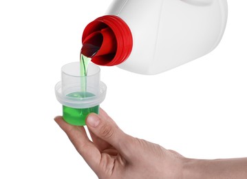 Photo of Woman pouring fabric softener from bottle into cap on white background, closeup