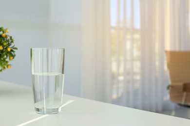Glass of water on table indoors. Space for text