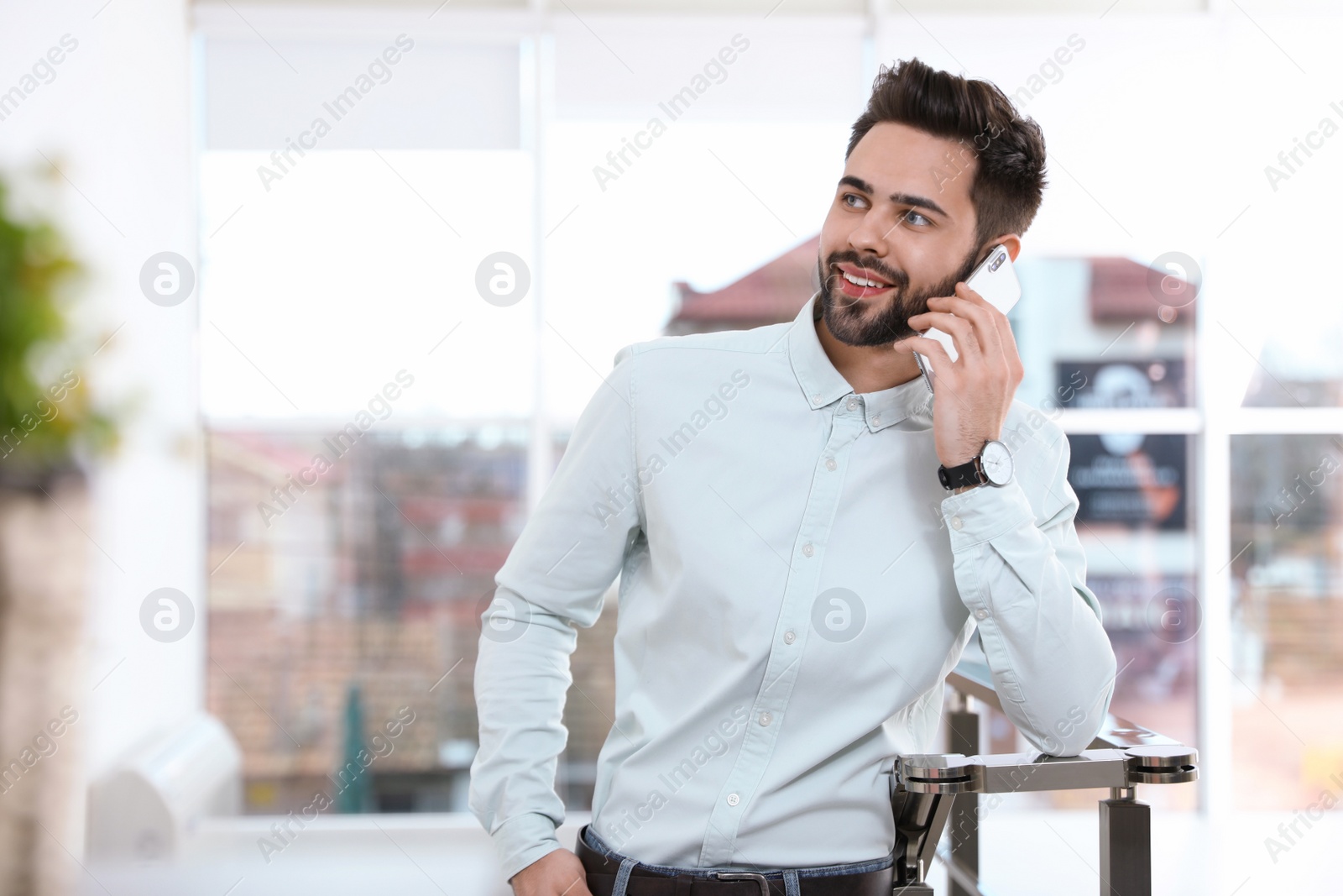 Photo of Portrait of handsome man talking on mobile phone in light room