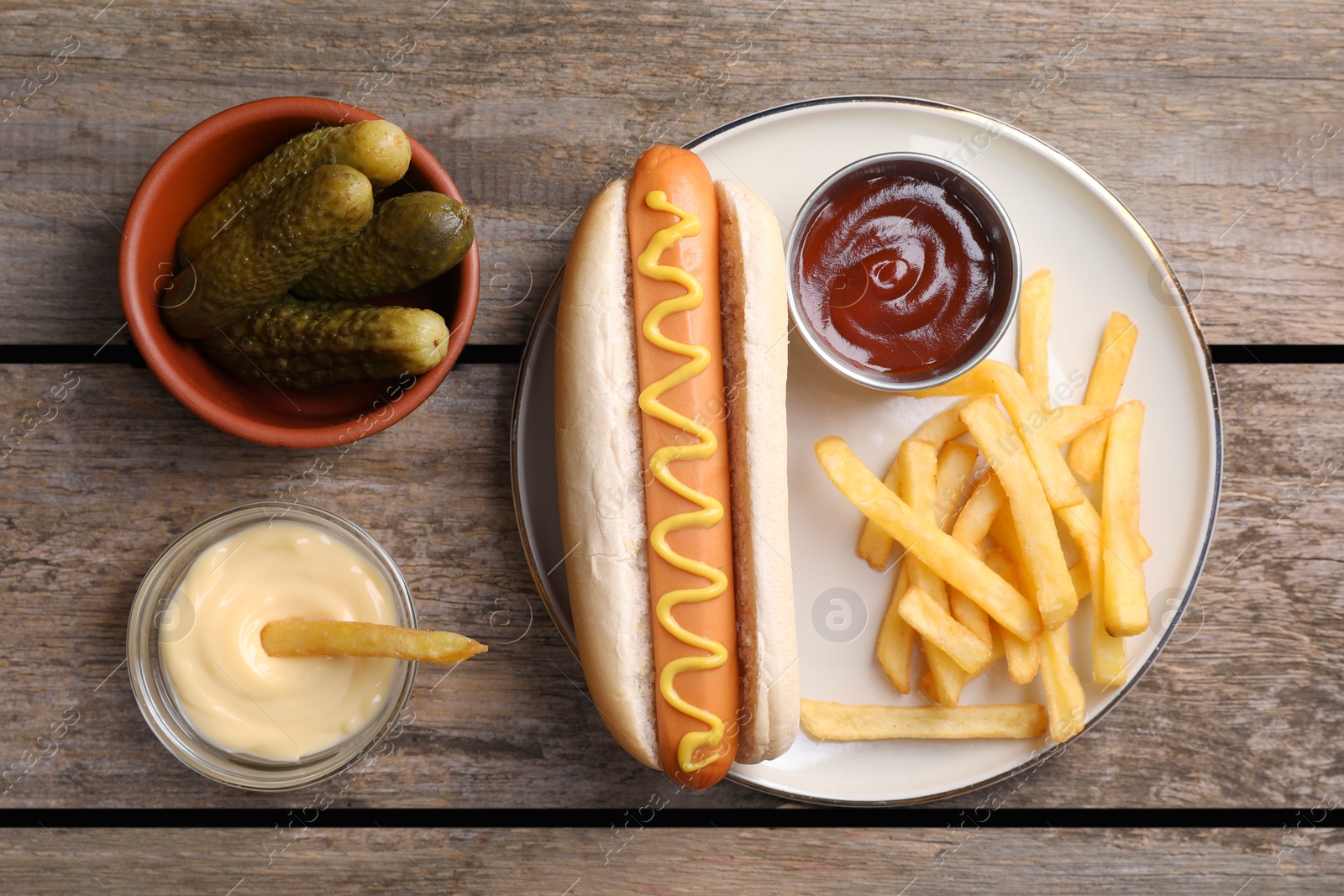 Photo of Flat lay composition with delicious hot dog and French fries on wooden table