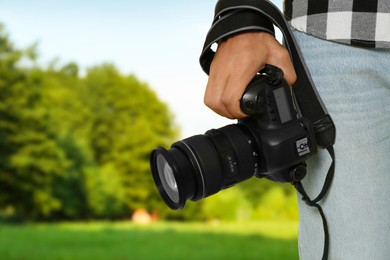 Professional photographer with modern camera and blurred view of landscape, space for text