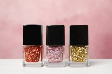 Photo of Bright nail polishes on table against color background