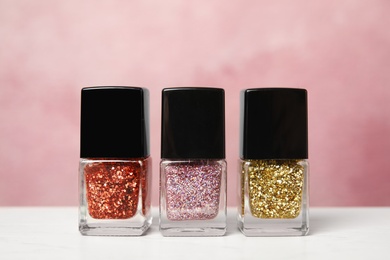 Bright nail polishes on table against color background