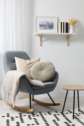Soft pillows and blanket on rocking armchair indoors