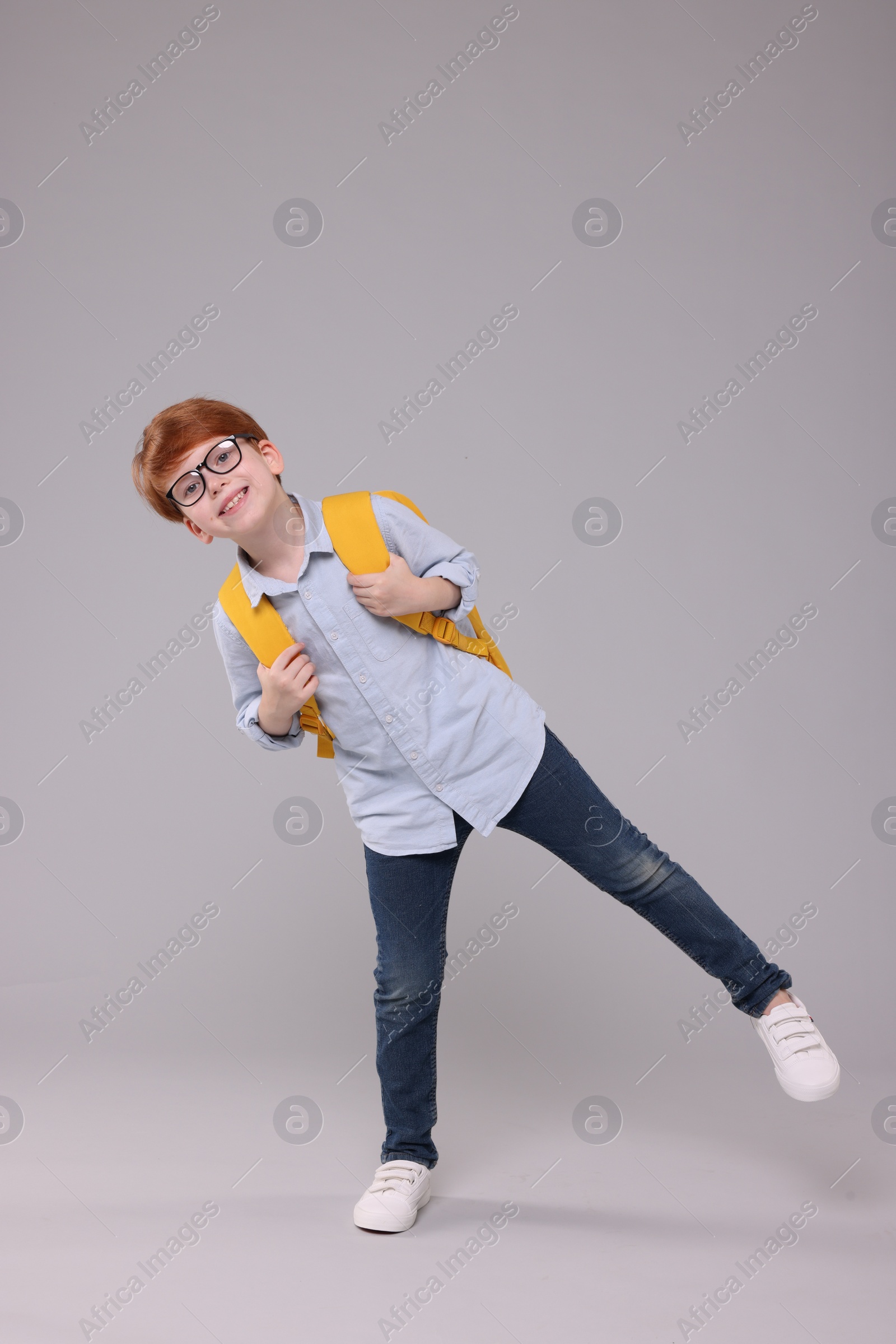 Photo of Happy schoolboy with backpack on grey background