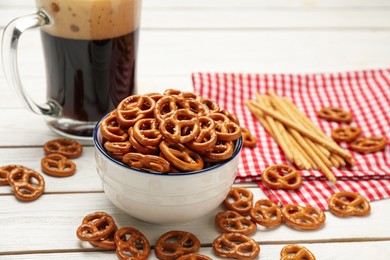 Delicious pretzel crackers and mug of beer on white wooden table