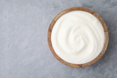 Photo of Delicious natural yogurt in bowl on grey table, top view. Space for text