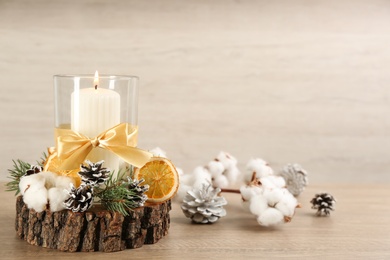Photo of Glass holder with burning candle and Christmas decor on wooden table. Space for text
