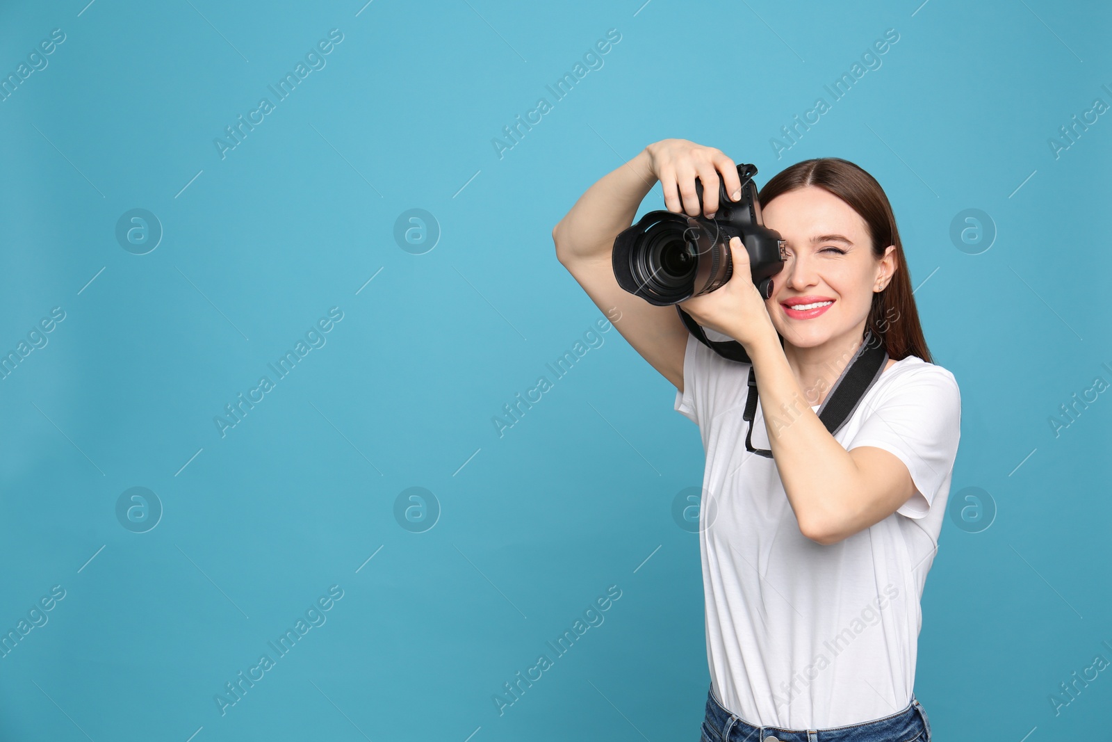 Photo of Professional photographer taking picture on light blue background. Space for text