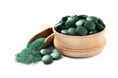 Wooden bowl of spirulina pills and powder in scoop on white background