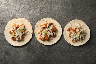 Delicious tacos with vegetables, meat and lime on grey textured table, flat lay