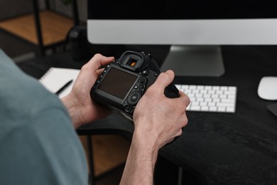 Photographer holding camera near dark table, closeup