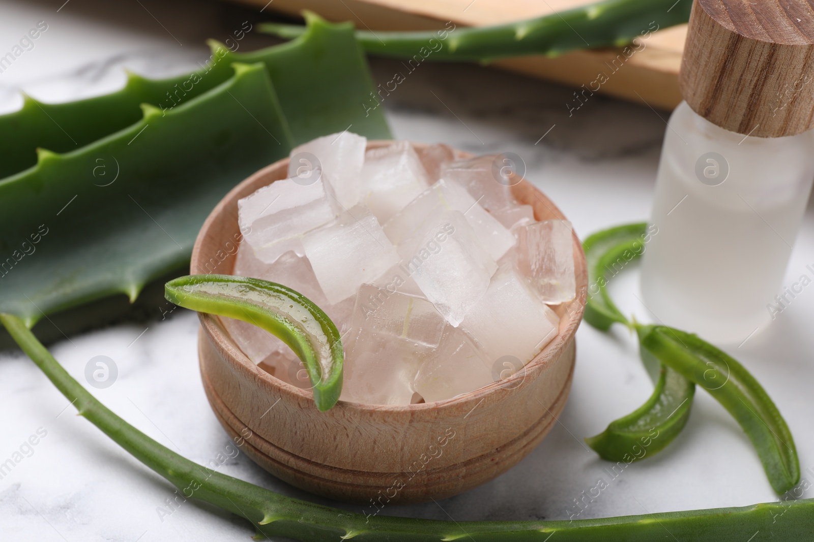 Photo of Aloe vera gel and slices of plant on white table, closeup