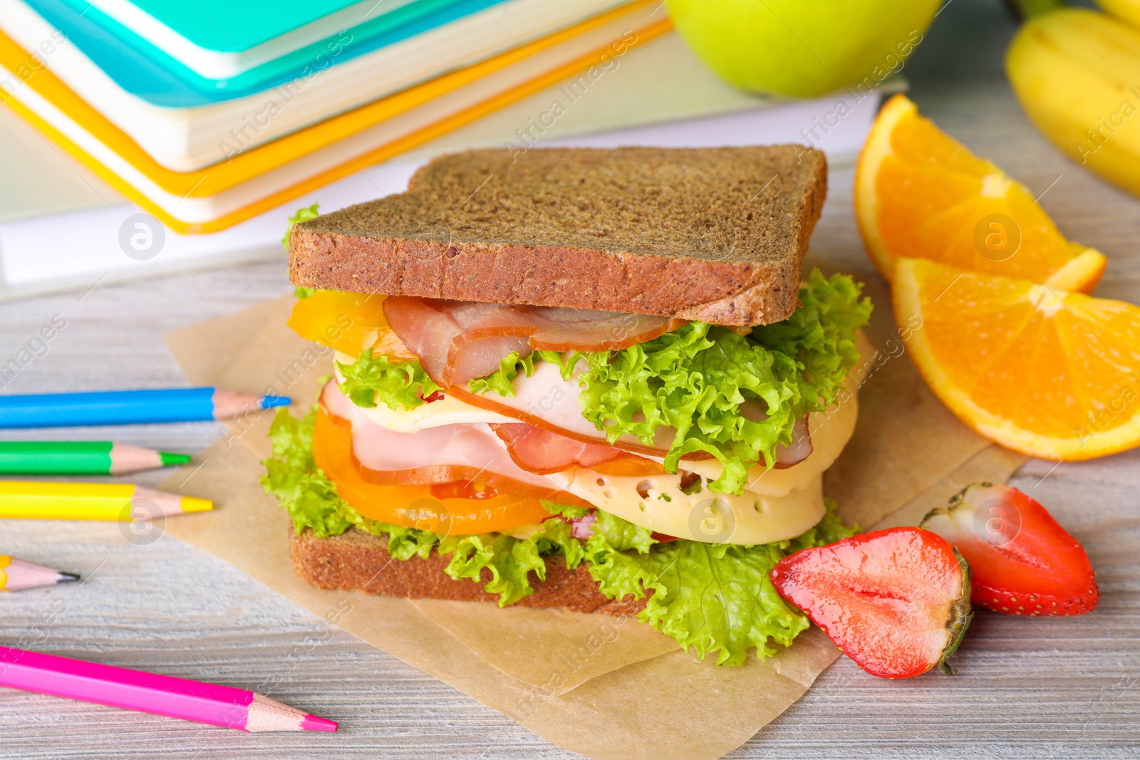 Photo of Tasty healthy food and different stationery on wooden table, closeup. School lunch