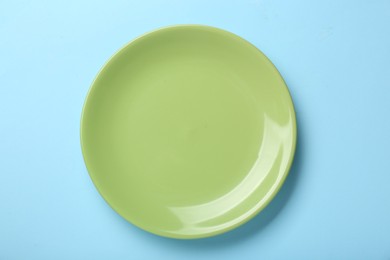 Empty green ceramic plate on light blue background, top view