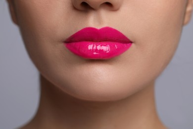 Closeup view of woman with beautiful full lips on grey background