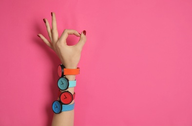 Woman wearing many bright wrist watches on color background, closeup view with space for text. Fashion accessory
