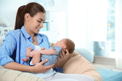 Photo of Young woman with her newborn baby at home. Space for text