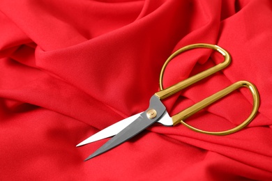 Sharp scissors on red fabric, space for text. Tailoring accessory
